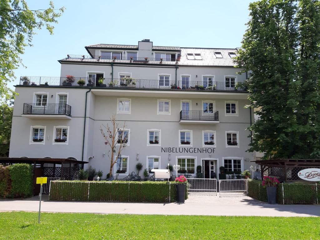 Pohled na hotel zvenčí se zelenou loukou v popředí a modrou imelou 