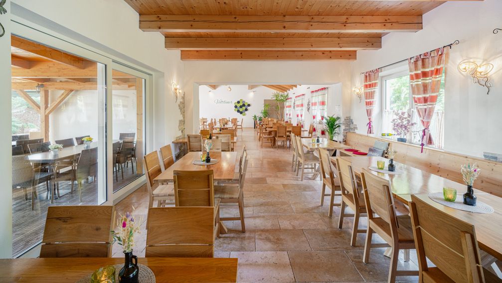 Pohled do interiéru útulné vinárny s dřevěným nábytkem a ozdobnými závěsy.