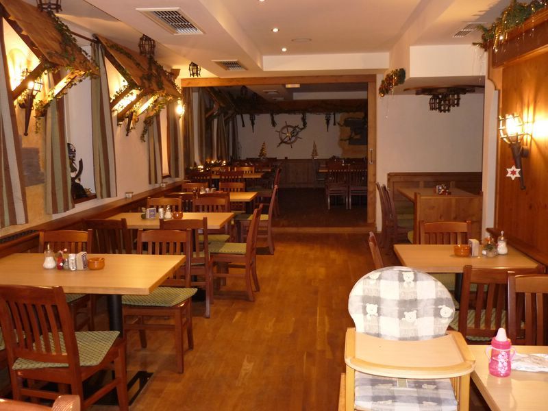 Pohled do interiéru rustikální restaurace s dřevěným nábytkem a dekoracemi.