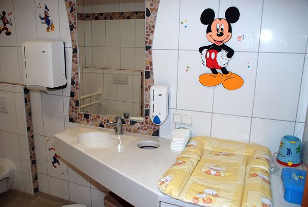 Dětská koupelna s dekorem Mickey Mouse a přebalovacím pultem.