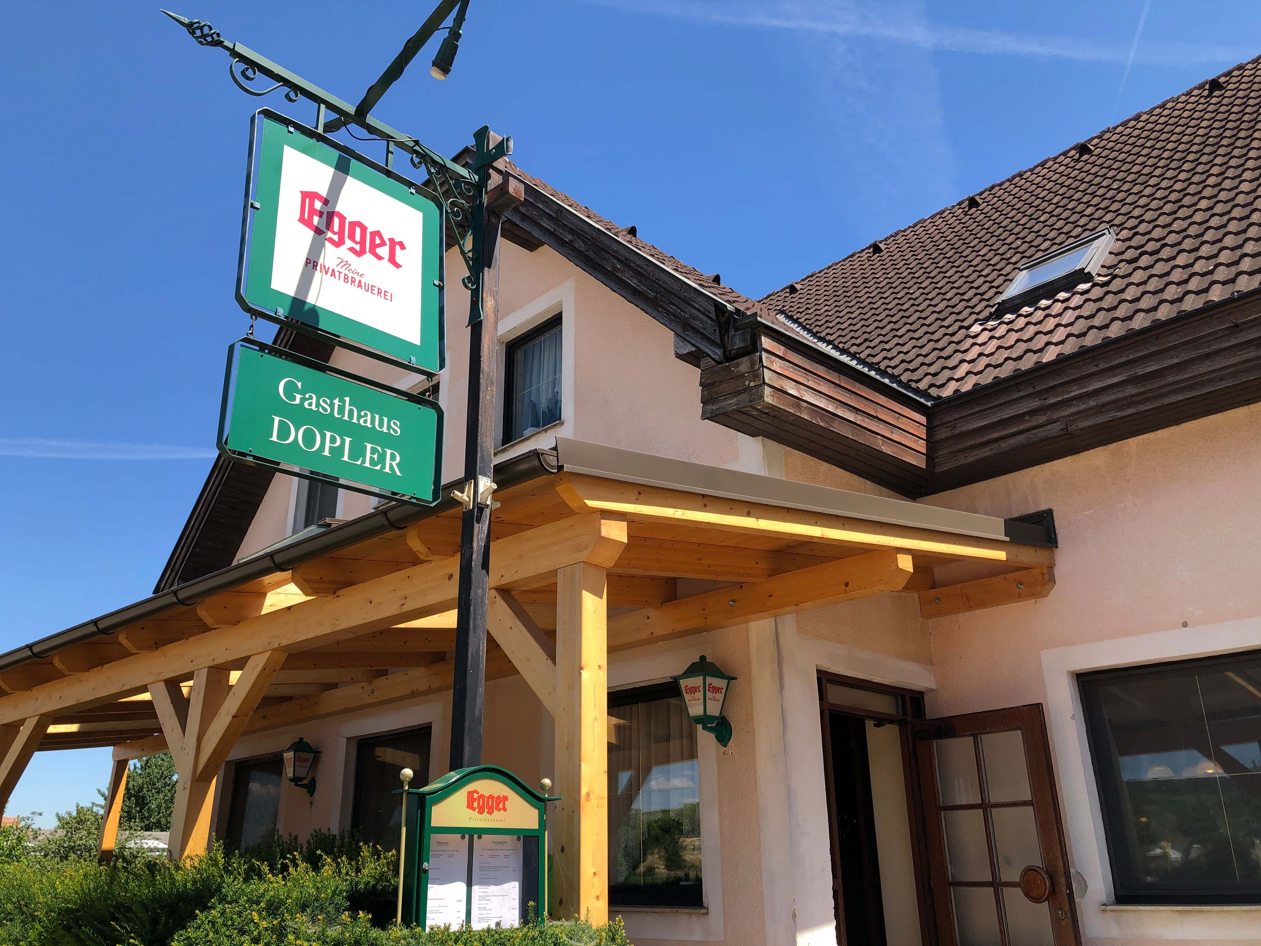 Gasthaus Doppler s nápisem pivovaru Egger a dřevěnou střechou.