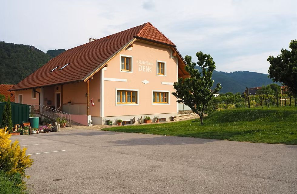 oranžový rodinný dům s asfaltovým parkovištěm před domem