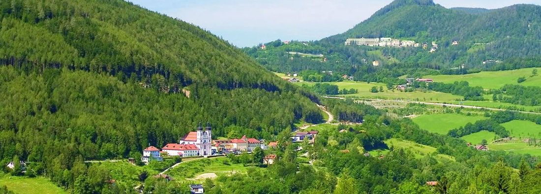 Krajina s kostelem a zelenými kopci v popředí.