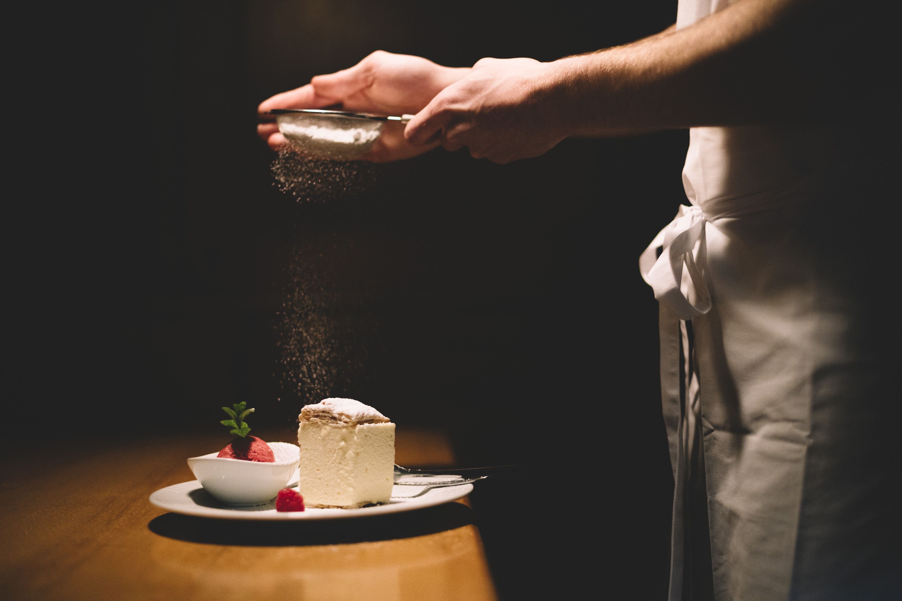 Talířek se šlehačkou a malinovým sorbetem, posypaný moučkovým cukrem.