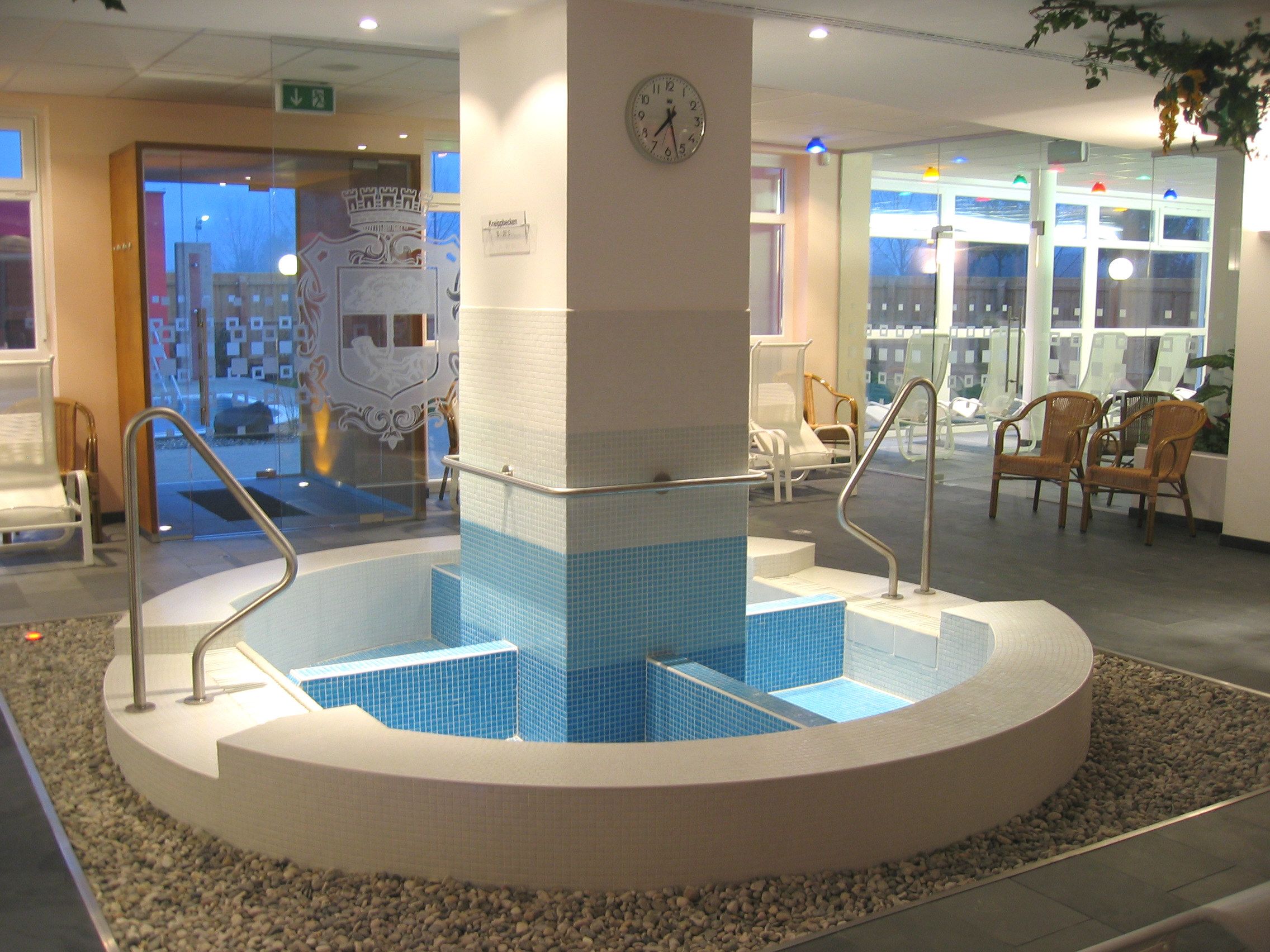 Pohled do interiéru Kneippova bazénu v rekreačním středisku Stockerau s modrými dlaždicemi a zábradlím.