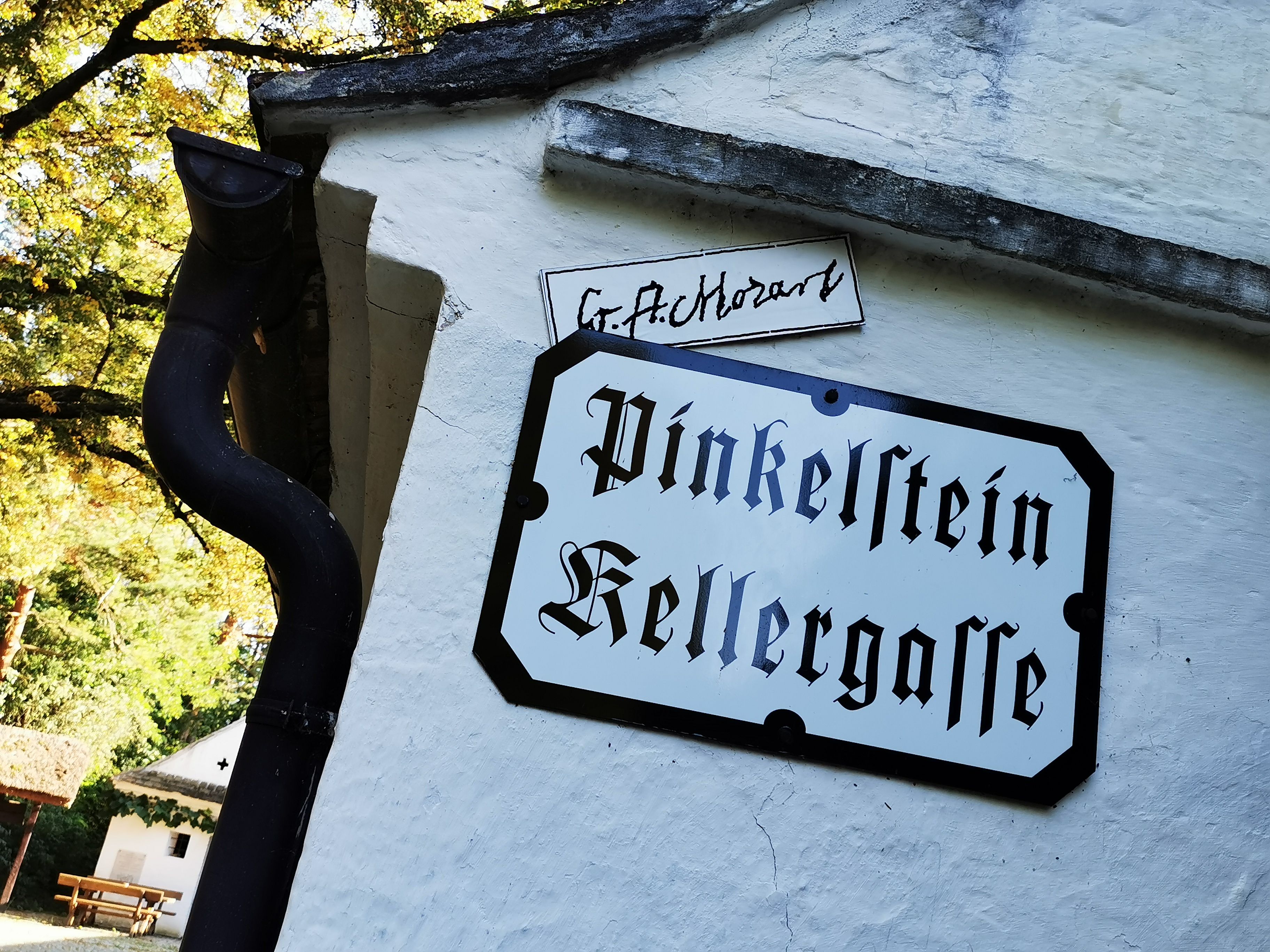 Tabulka s nápisem "Pinkelstein sklepní uličky" na bílé zdi.