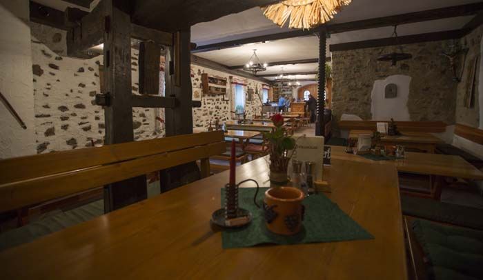 Rustikální restaurace s dřevěnými stoly a kamennými zdmi.