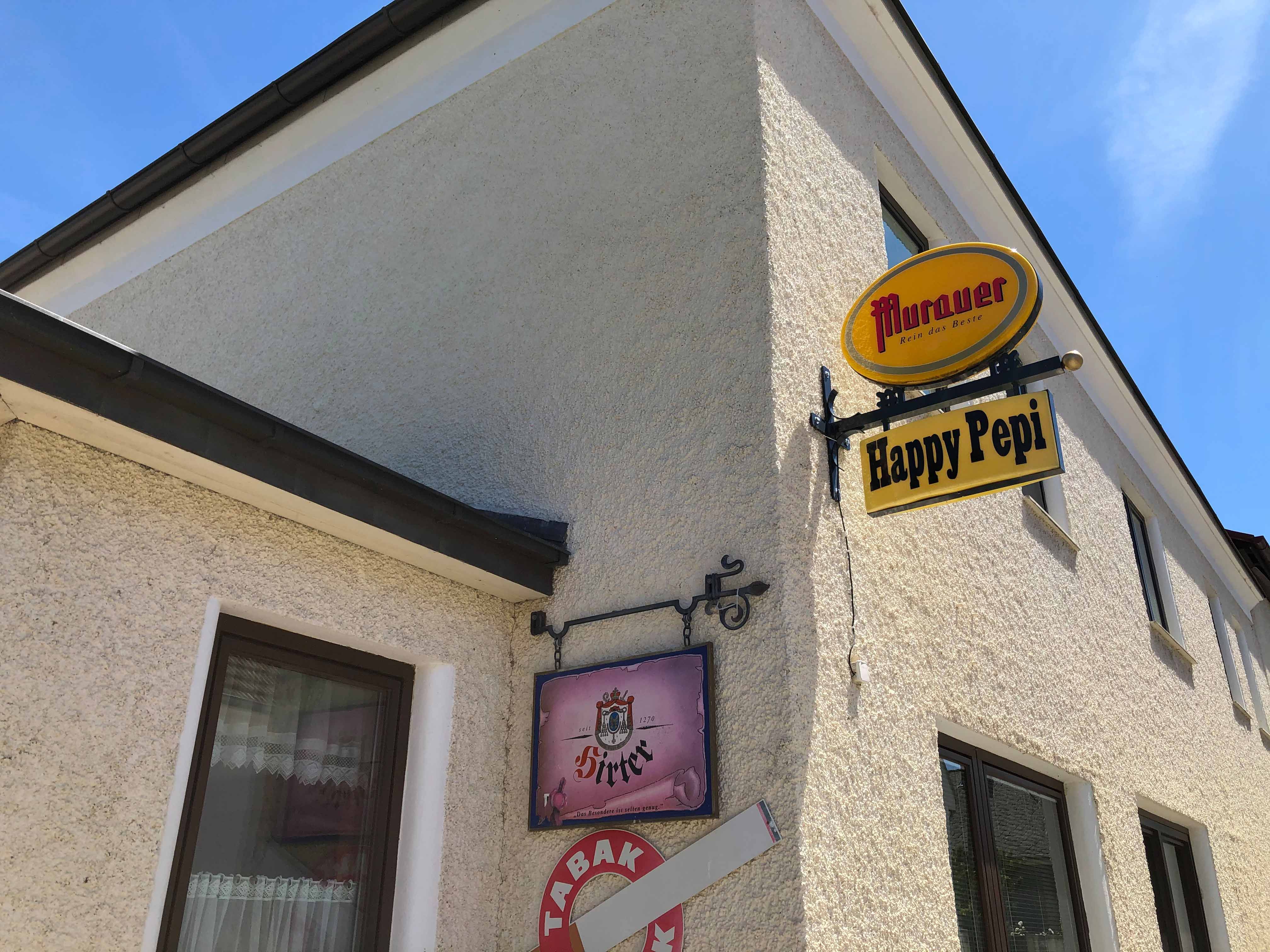 Pohled na budovu s nápisy "Murauer" a "Happy Pepi" zvenčí.