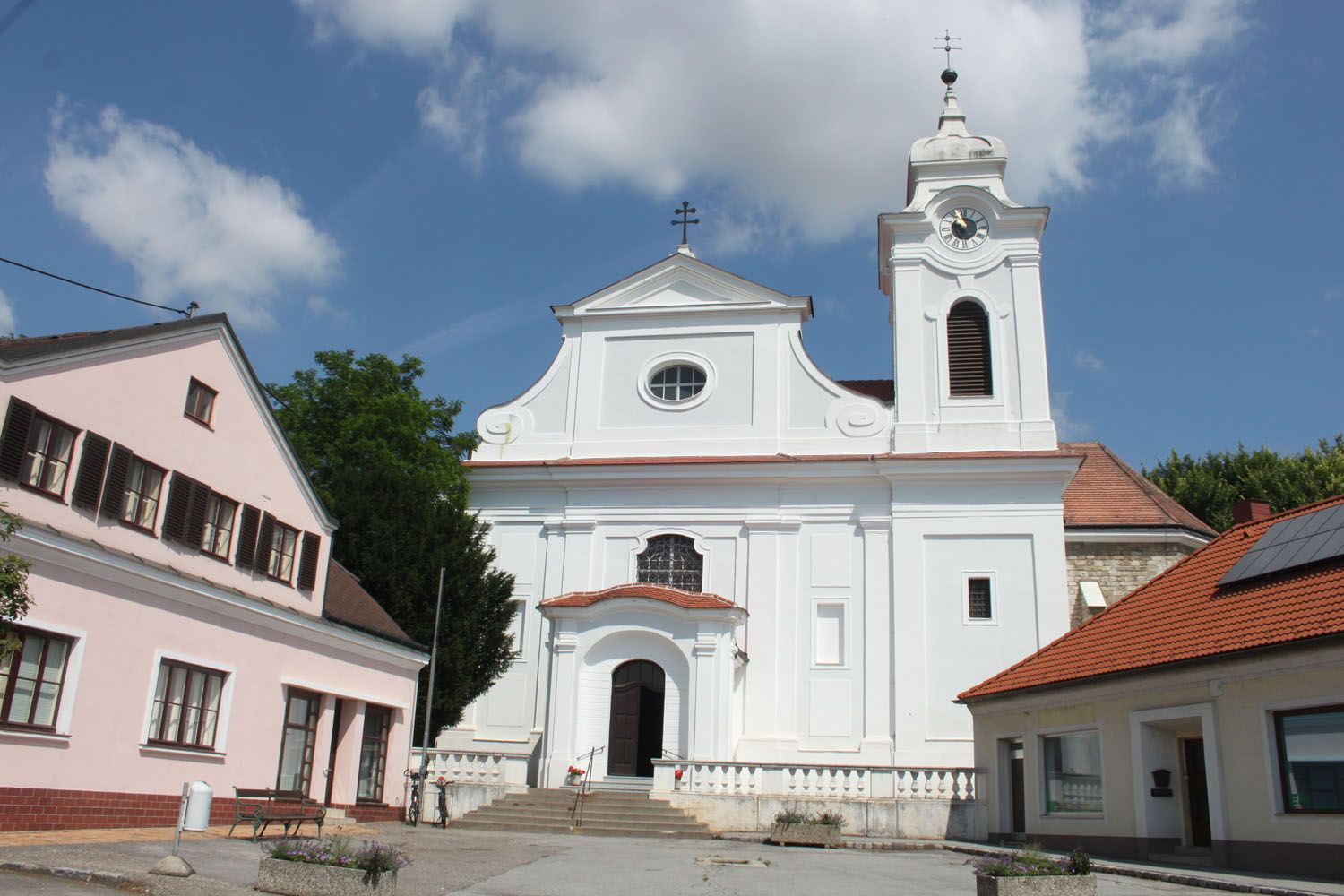 Farní kostel ve Wilfersdorfu s bílou fasádou a zvonicí.