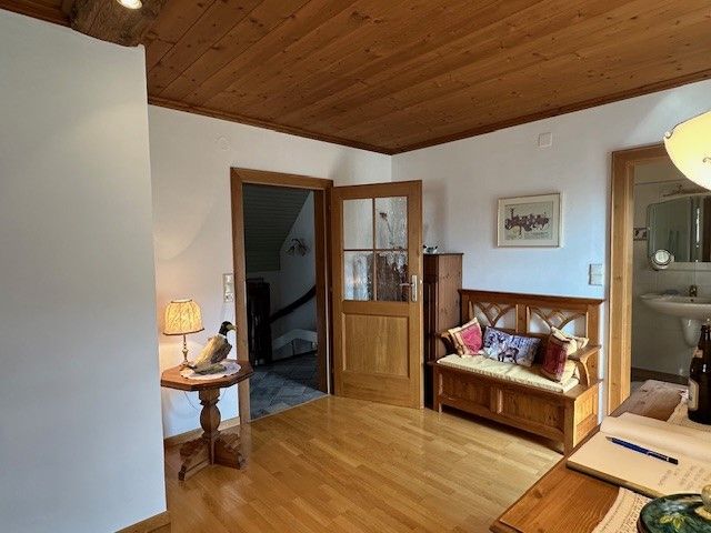 Dřevem obložený pokoj s lavicí, stolní lampou a otevřeným přístupem do koupelny.