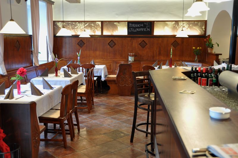 Pohled do interiéru útulné restaurace s dřevěným nábytkem a prostřenými stoly.