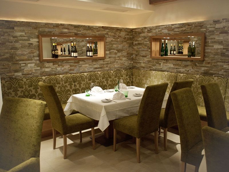 Elegantní restaurace s prostřeným stolem a zelenými židlemi.