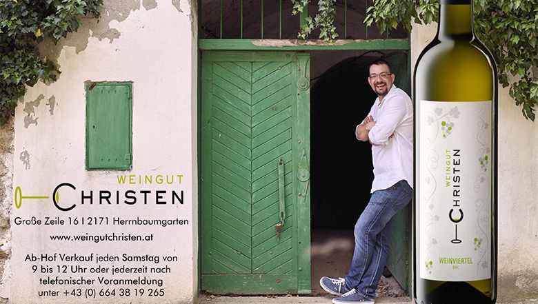 Muž se opírá o zelené dveře vedle lahve vína s nápisem "Weingut Christen".