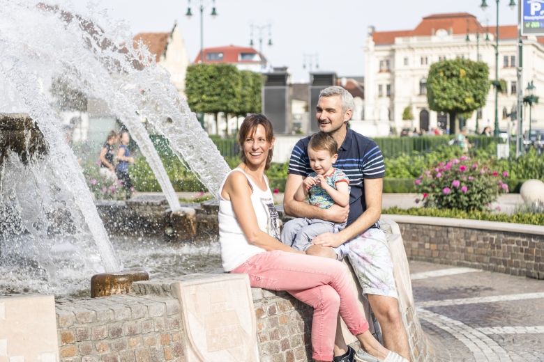 Usměvavá rodina sedí u kašny na hlavním náměstí v Tullnu.