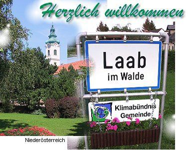 Uvítací cedule Laab im Walde s kostelem v pozadí.