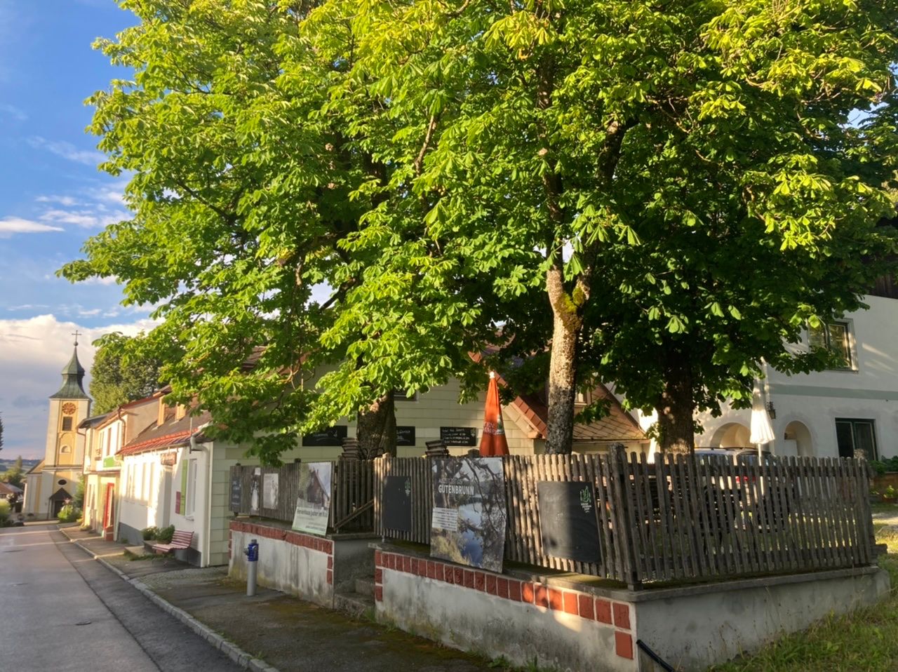 Tradiční hospoda s kaštanovou zahradou a kostelem v pozadí.
