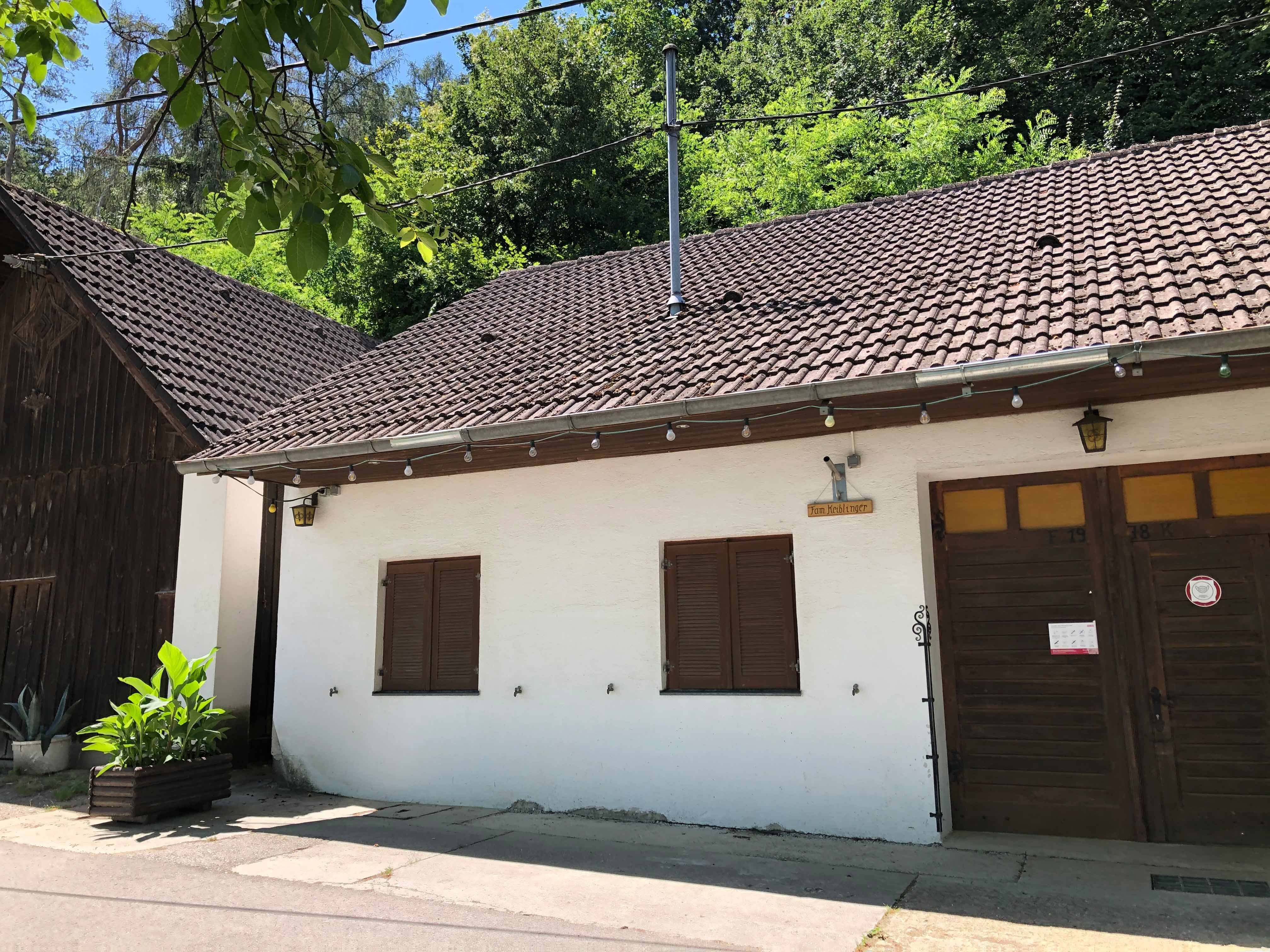 Pohled zvenčí na vinárnu s bílou fasádou a dřevěnými dveřmi.