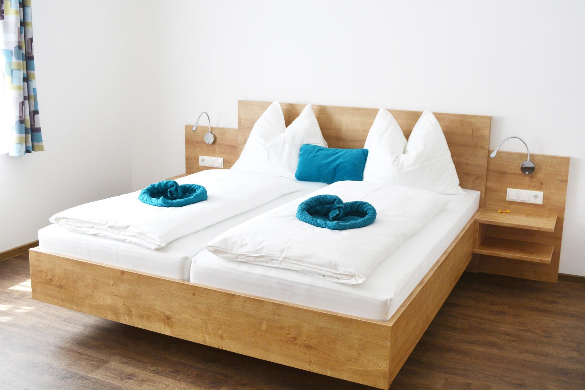 Moderní pokoj pro hosty s manželskou postelí, bílými peřinami a modrými polštáři.