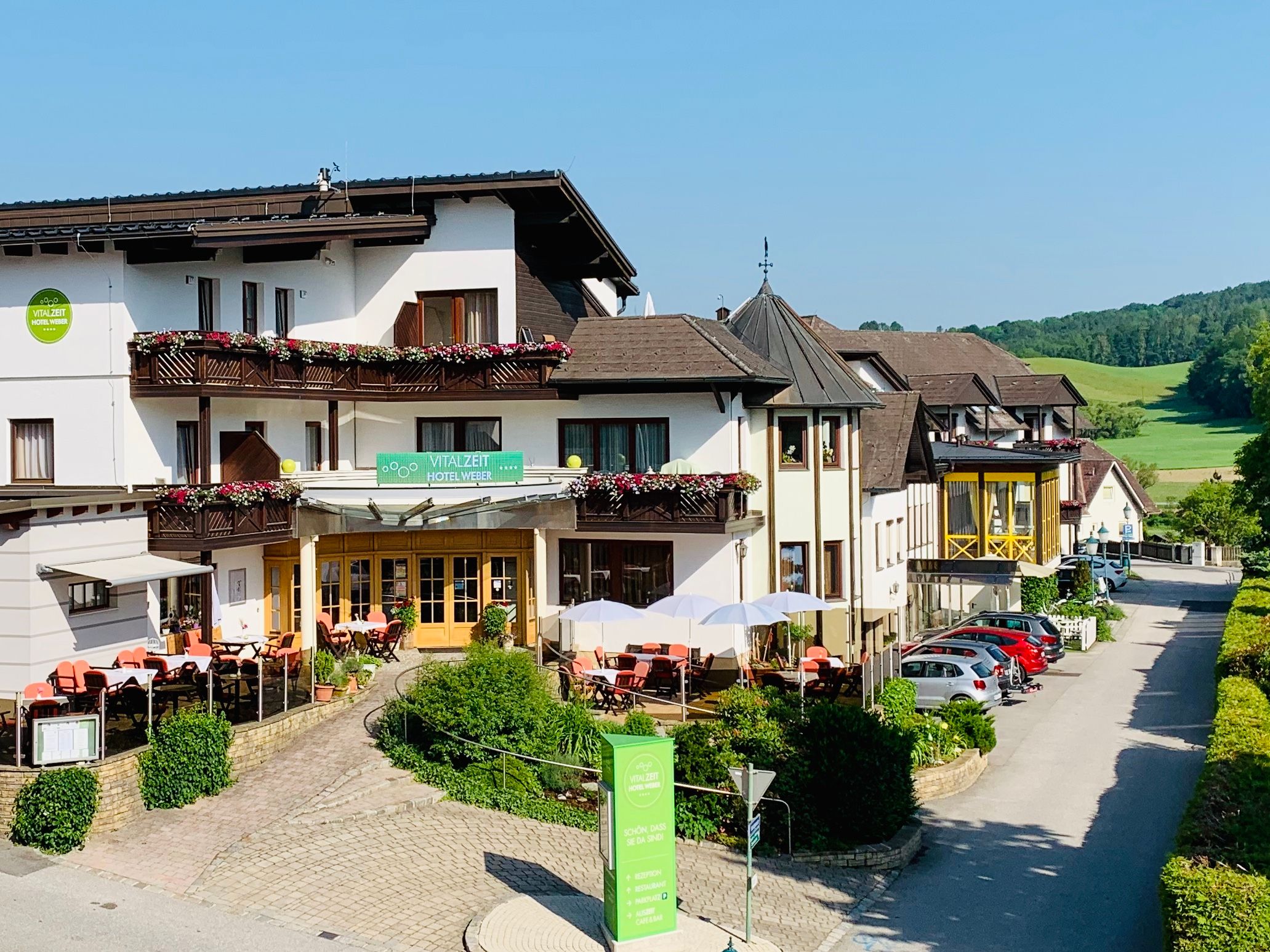 Pohled na exteriér hotelu VitalZeit Weber s terasou a květinami.