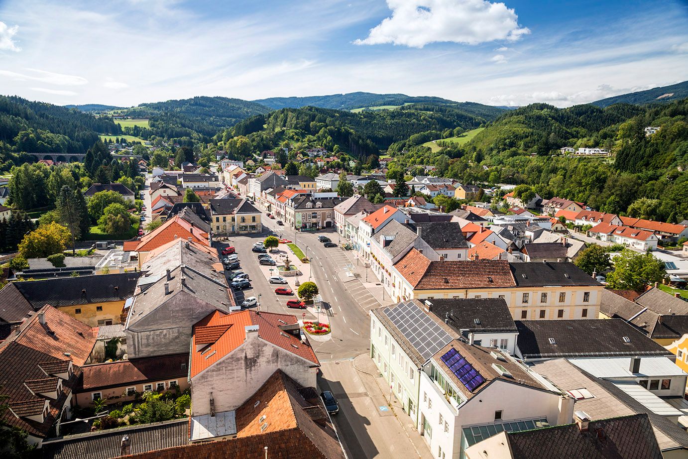 Letecký pohled na náměstí Aspang Markt s červenými střechami a zelenou krajinou v pozadí.
