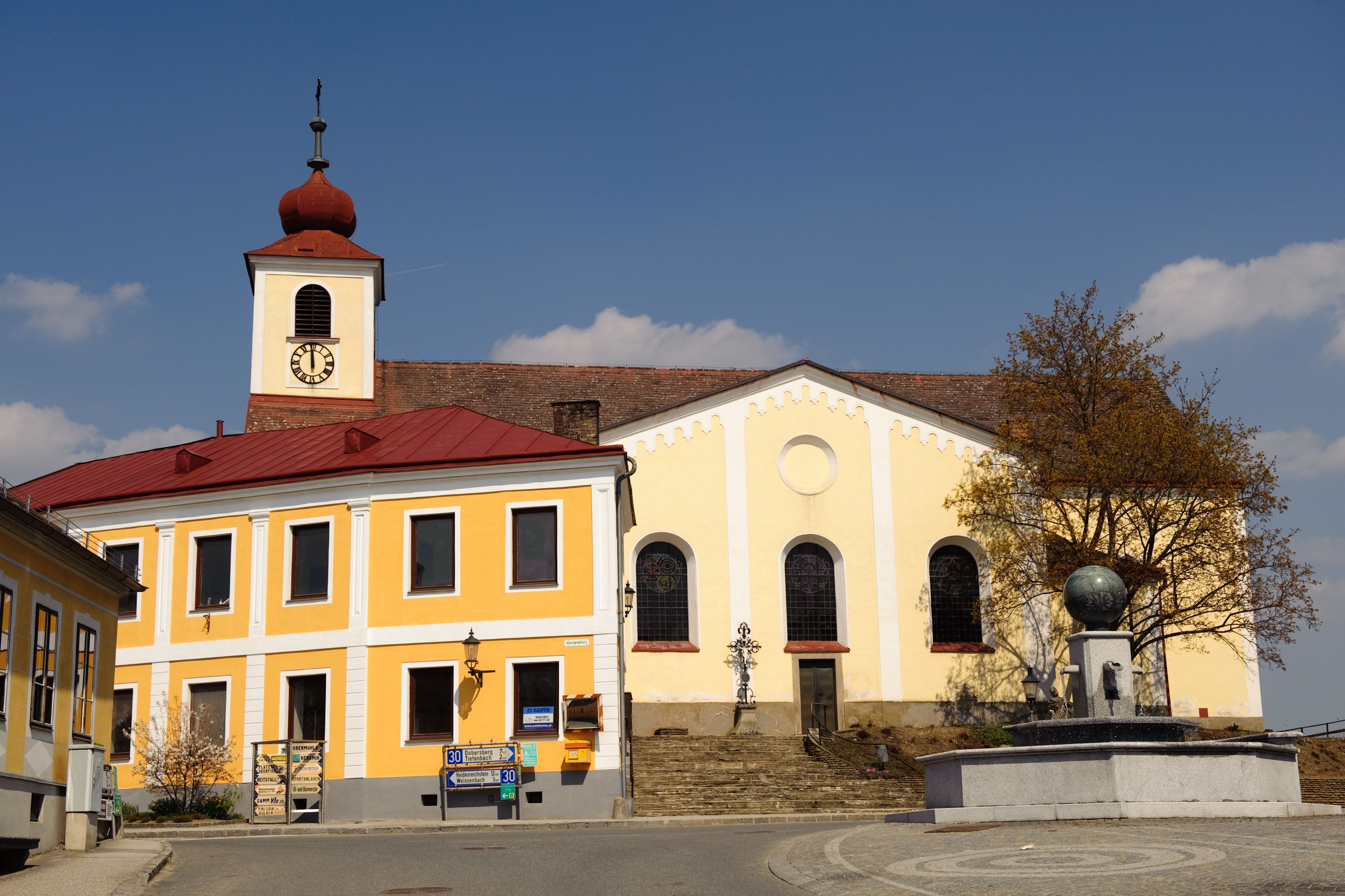 Kostel se žlutou fasádou a věží s červenou střechou na hlavním náměstí.