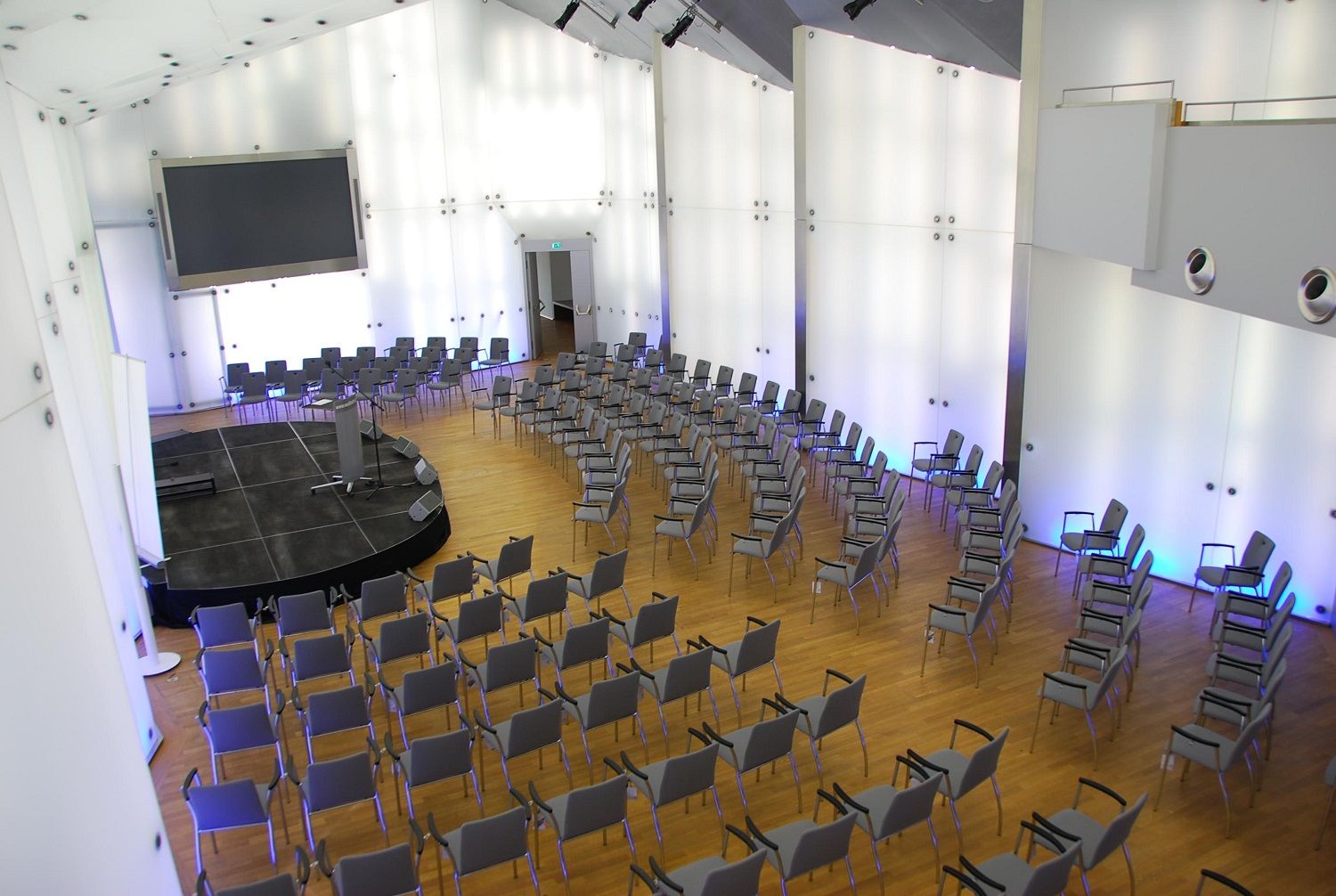 Moderní konferenční sál s řadami židlí a pódiem na zámku Rothschild, Kristallsaal.