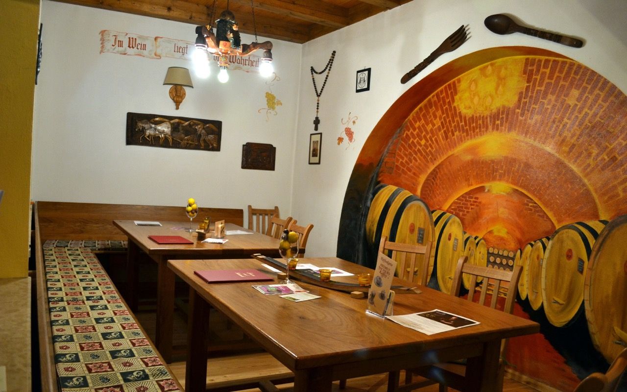 Útulný salonek Lössiade s dřevěnými stoly, teplým osvětlením a tradičním nábytkem.