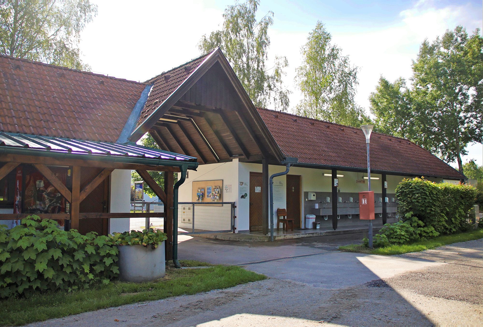 Pohled zvenčí na budovu s červenými taškovými střechami a venkovními umyvadly.