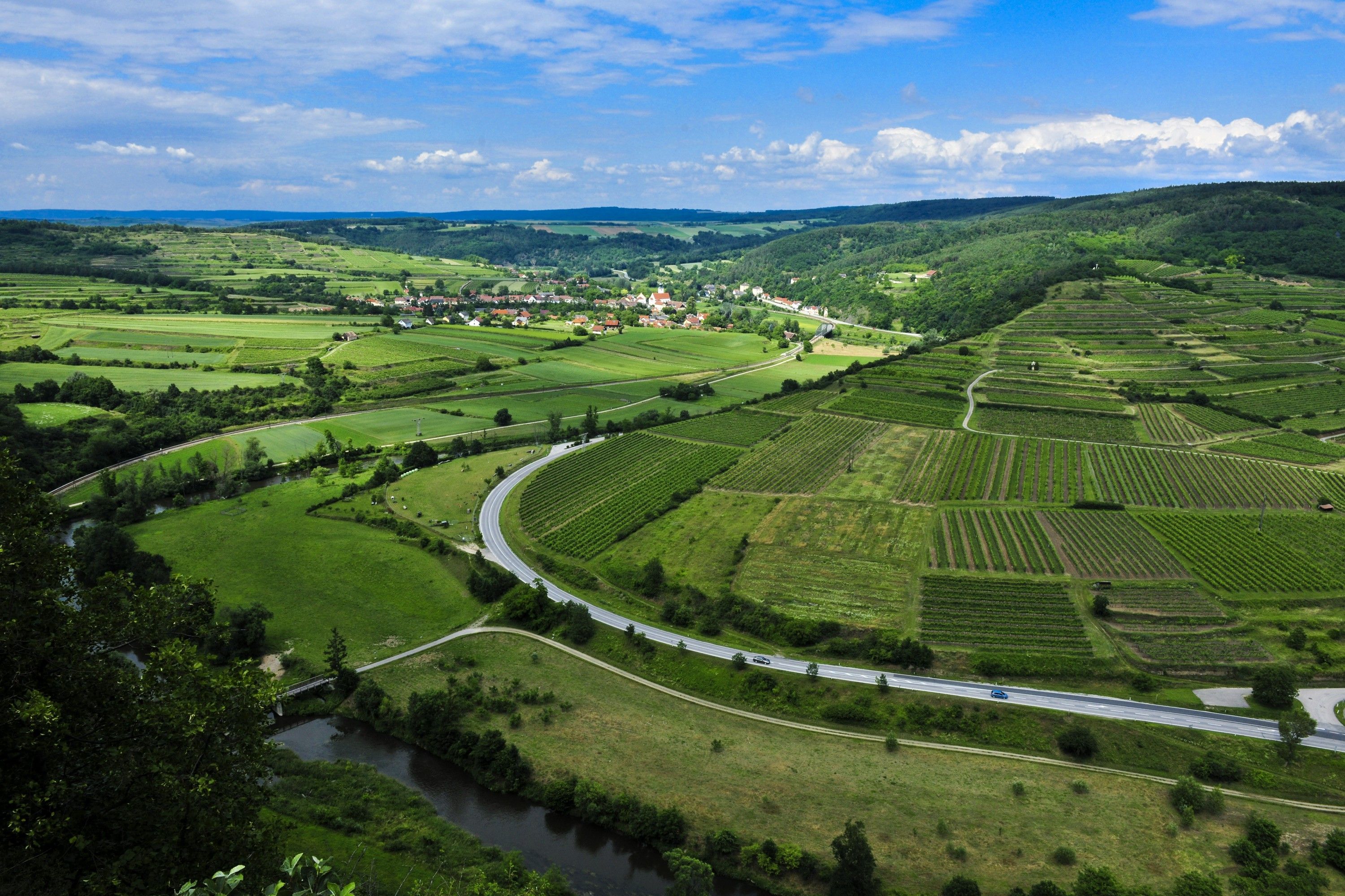 Krajina v přírodním parku Kamptal Schönberg s poli, cestami a řekou.