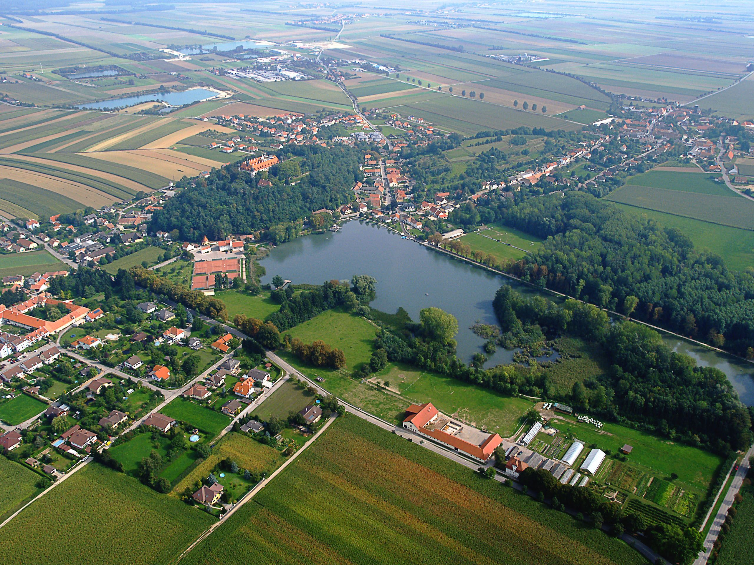 Letecký pohled na Sitzenberg-Reidling se zámkem, jezerem a okolními poli.