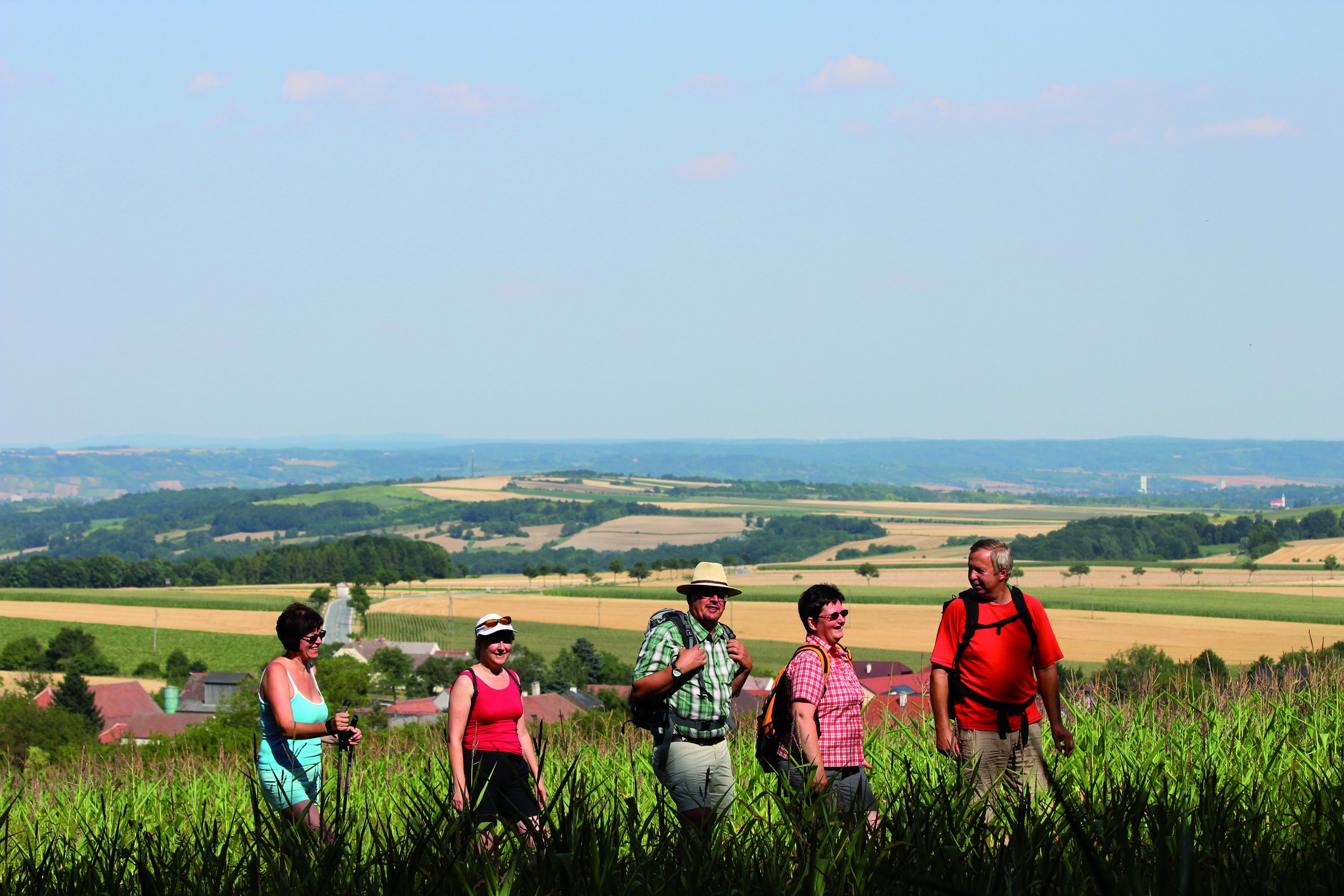 Skupina turistů na venkovské cestě s rozlehlou krajinou v pozadí.