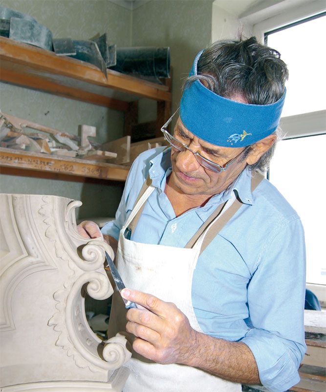Restaurátor pracuje na dekorativním prvku pomocí nástroje.