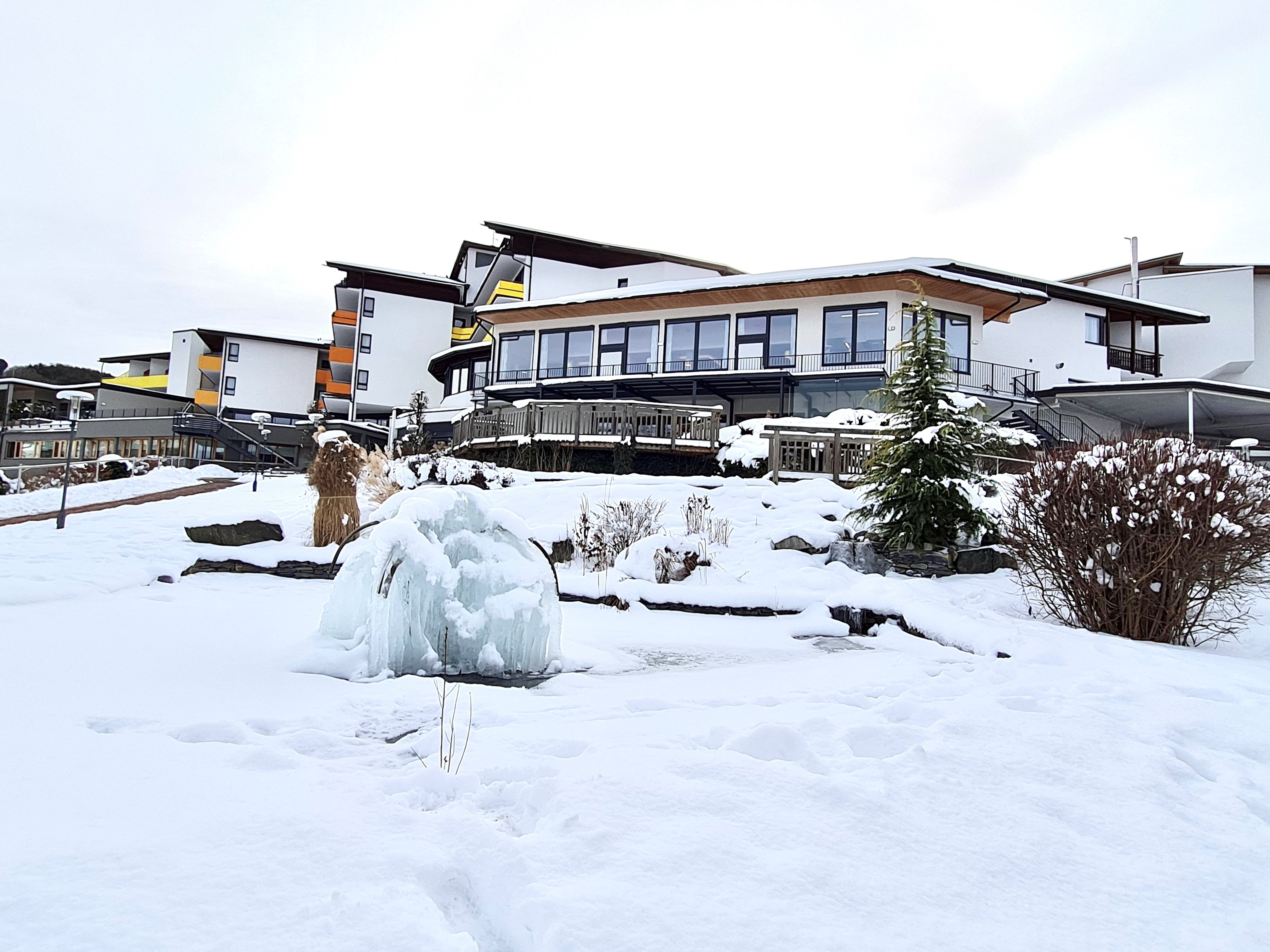 Zasněžená budova hotelu se zamrzlou fontánou v popředí.