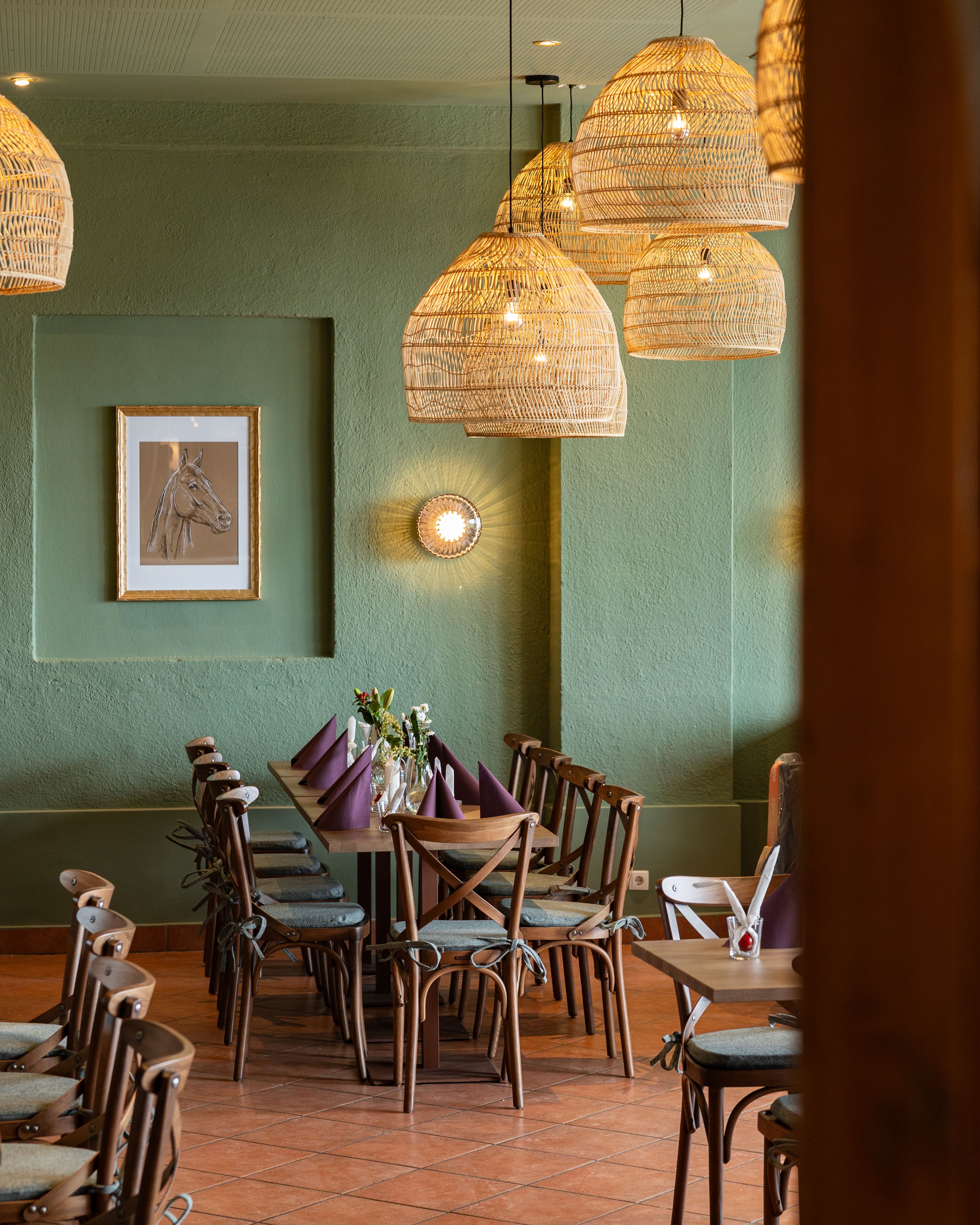 Útulný jídelní kout s dřevěným stolem, židlemi a tkanými lampami.