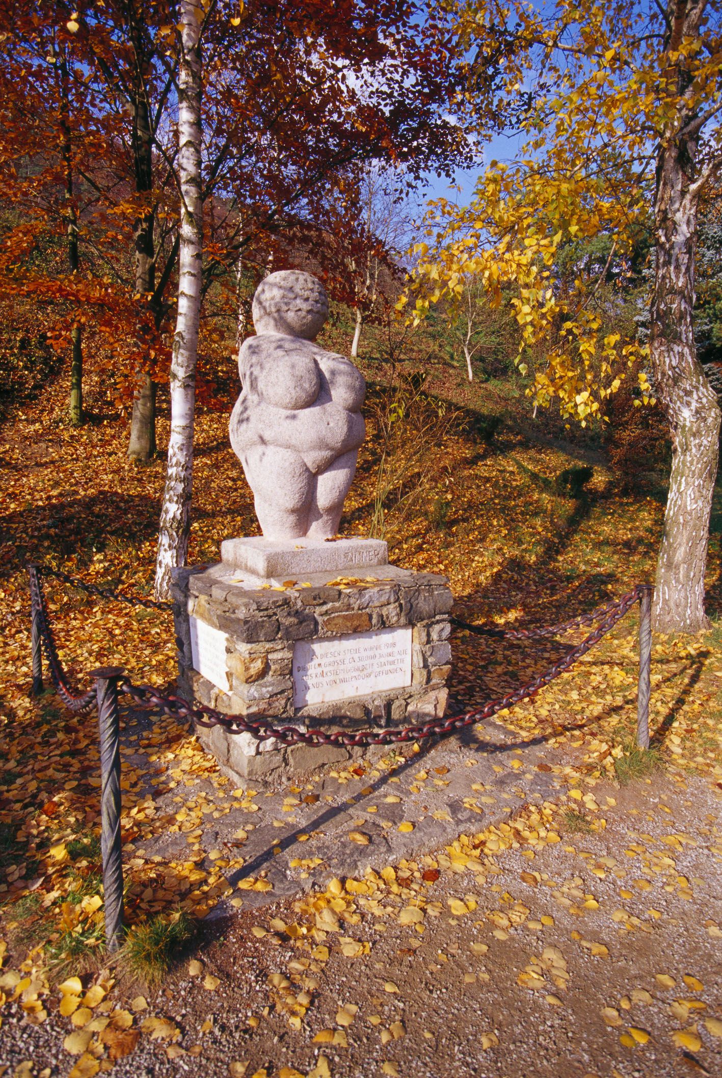 Venuše na podstavci s podzimním listím kolem ní