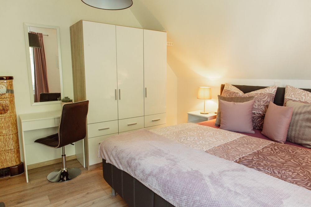 Ložnice s manželskou postelí, šatní skříní, toaletním stolkem a lampou.