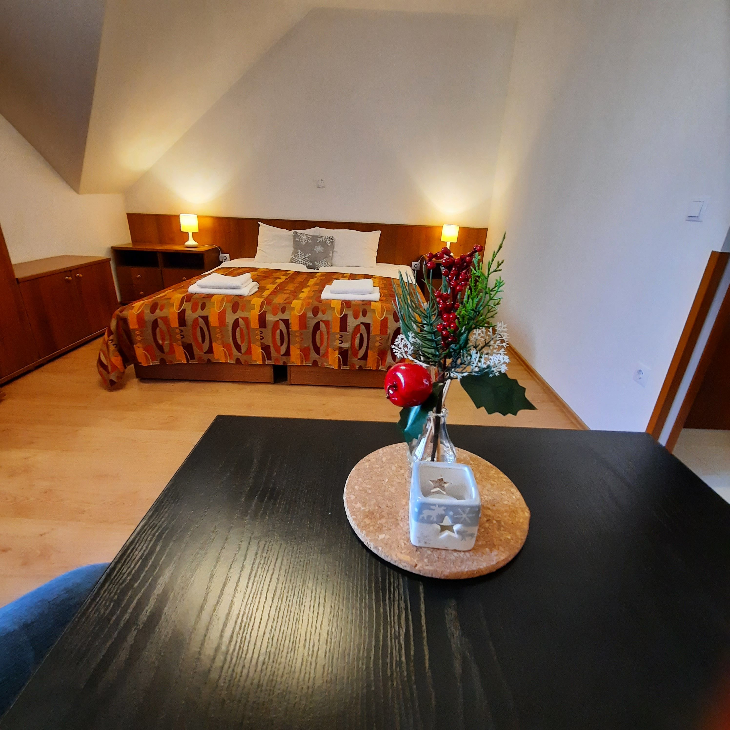 Útulný dvoulůžkový pokoj s dekorovaným stolem v popředí a postelí v pozadí.