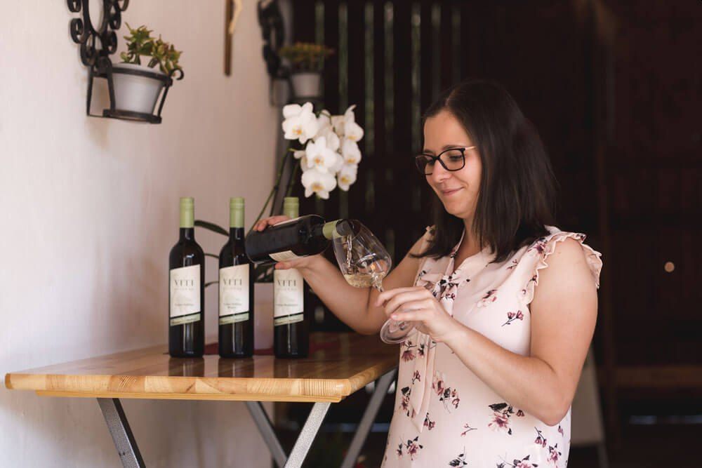 Žena nalévá víno do sklenice.