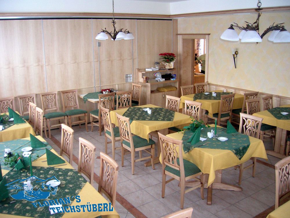 Pohled do interiéru restaurace s dřevěným nábytkem a žlutozelenými ubrusy.
