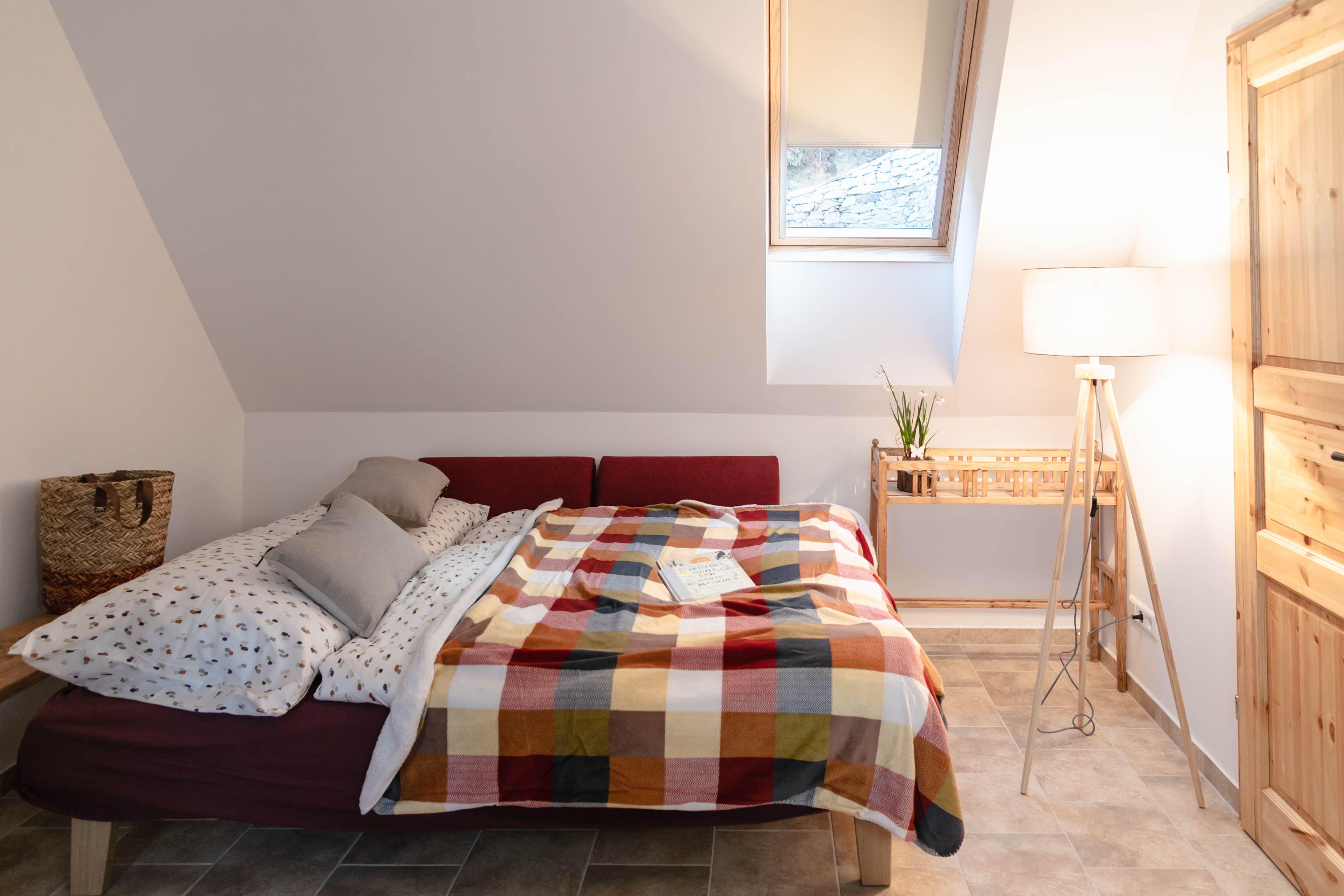 Útulná ložnice s postelí, barevnou dekou a lampičkou na čtení.