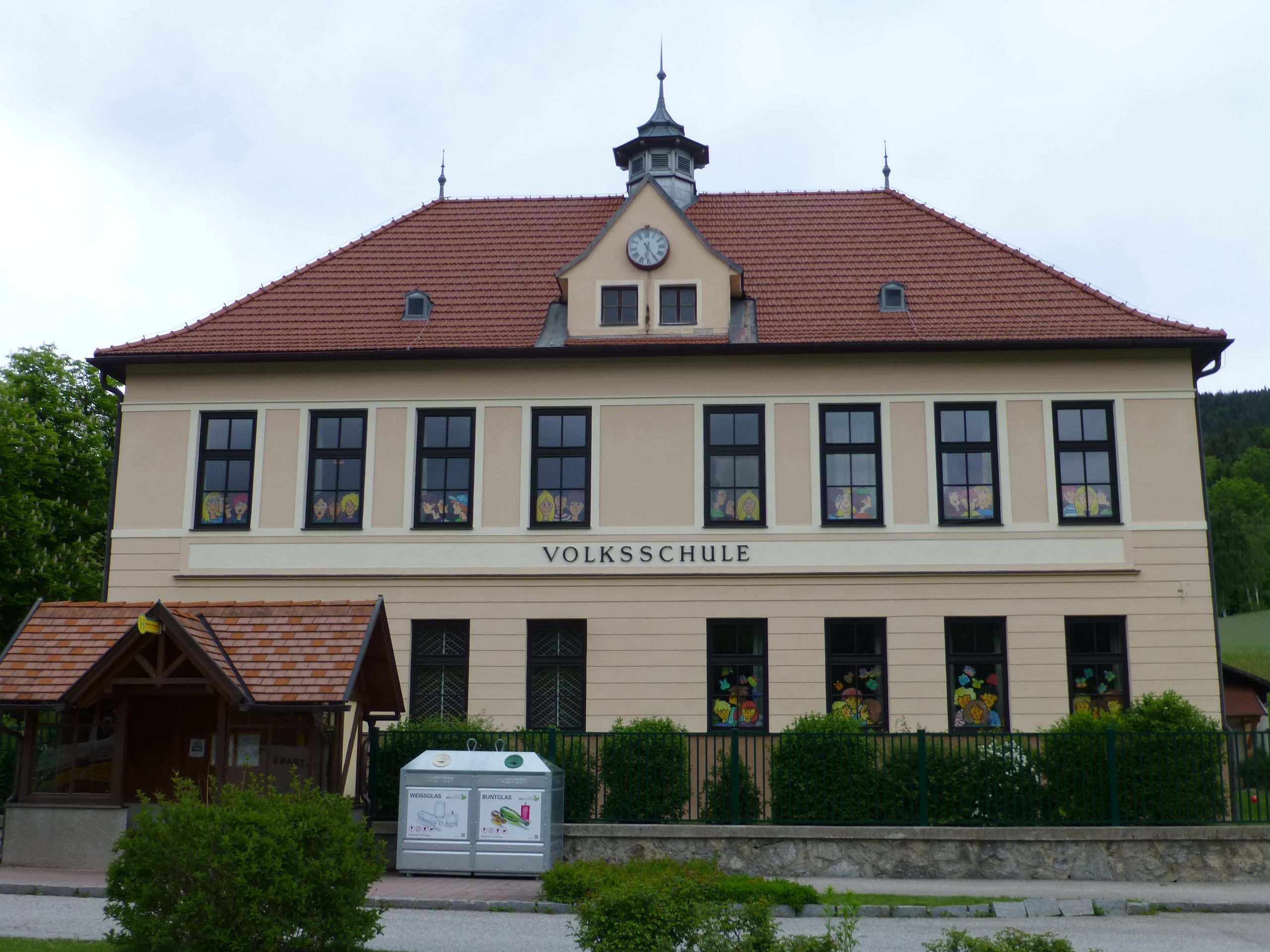 Pohled na základní školu v Otterthalu s červenými střešními taškami a zdobenými okny.