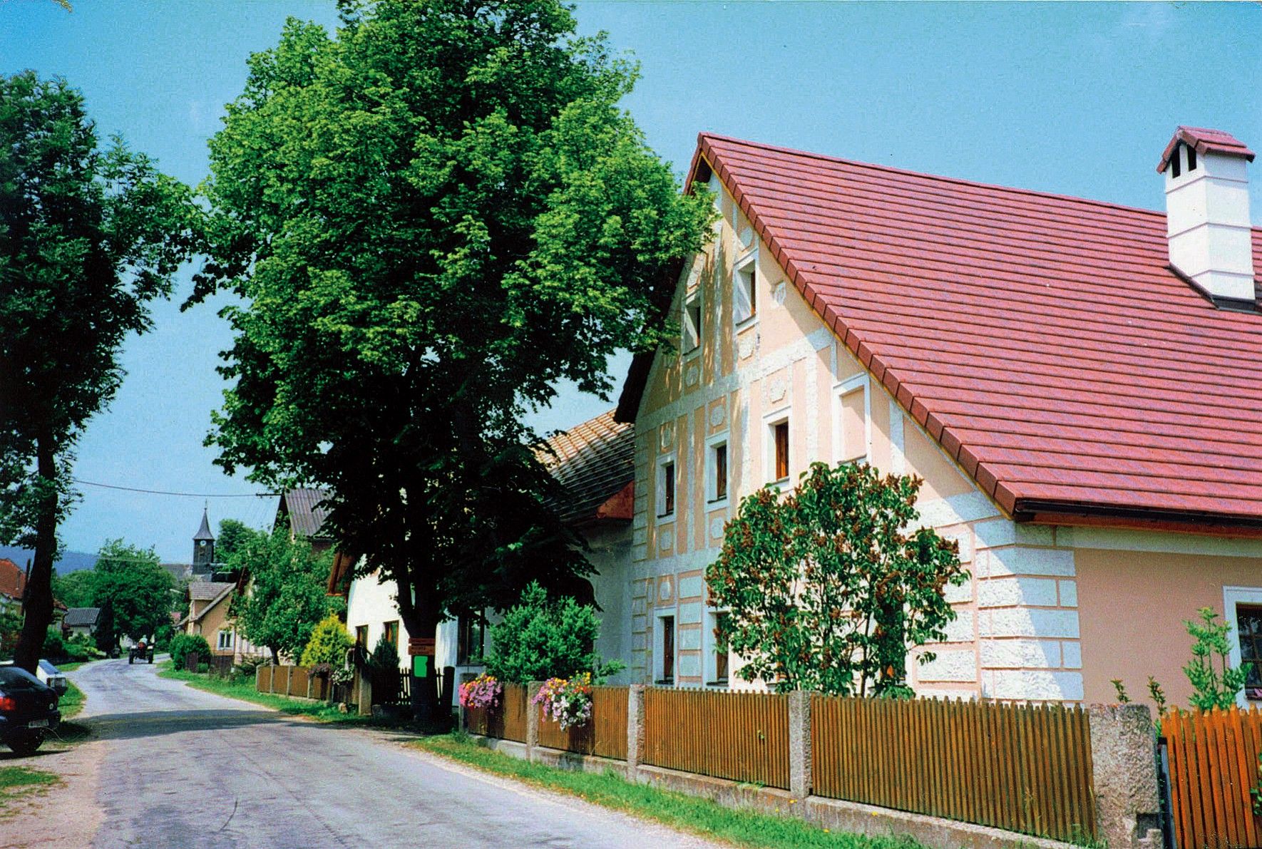 Ulice s tradičními domy a stromy ve venkovském prostředí.