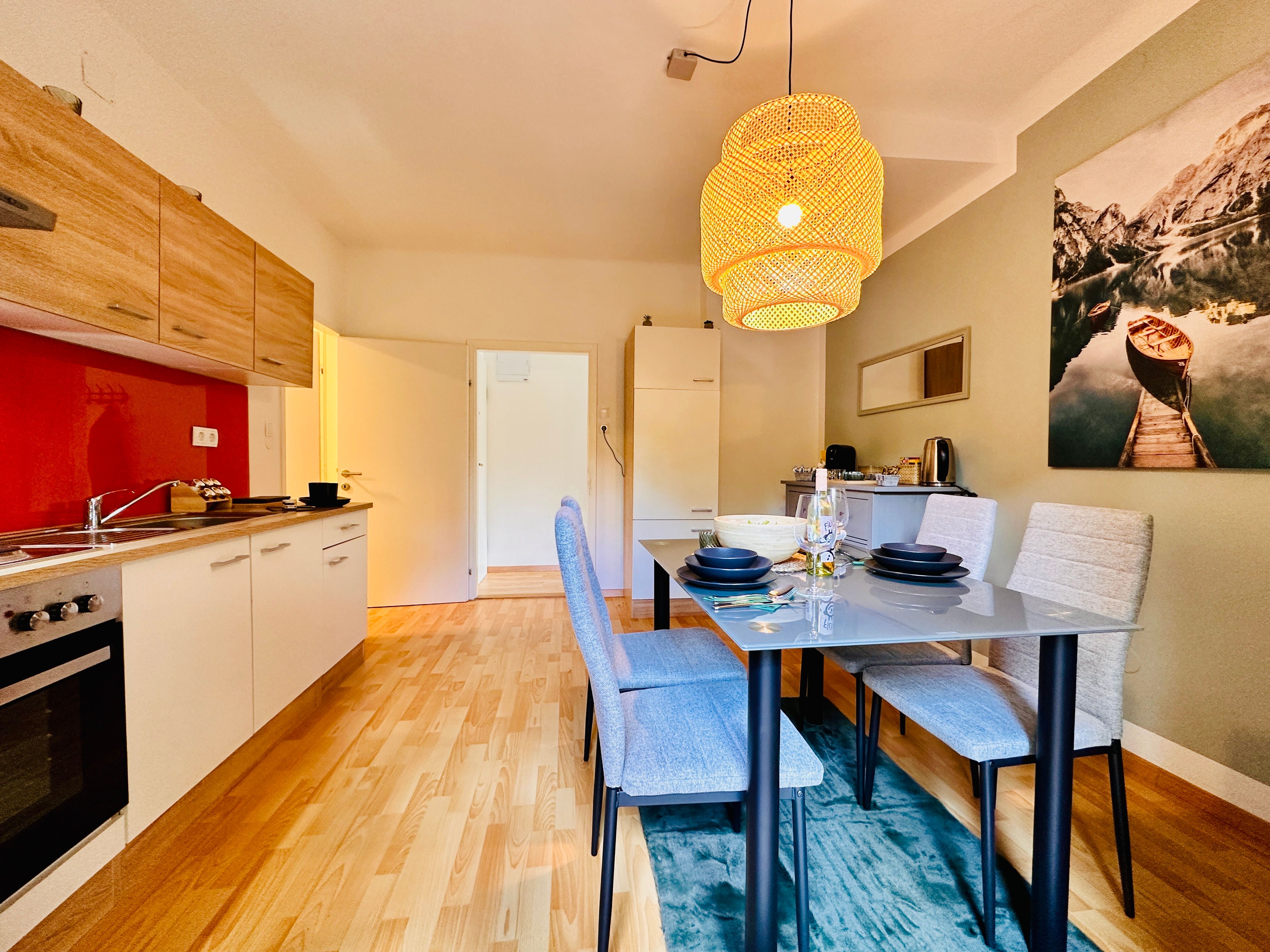 Moderní kuchyně s jídelním stolem a závěsnou lampou.