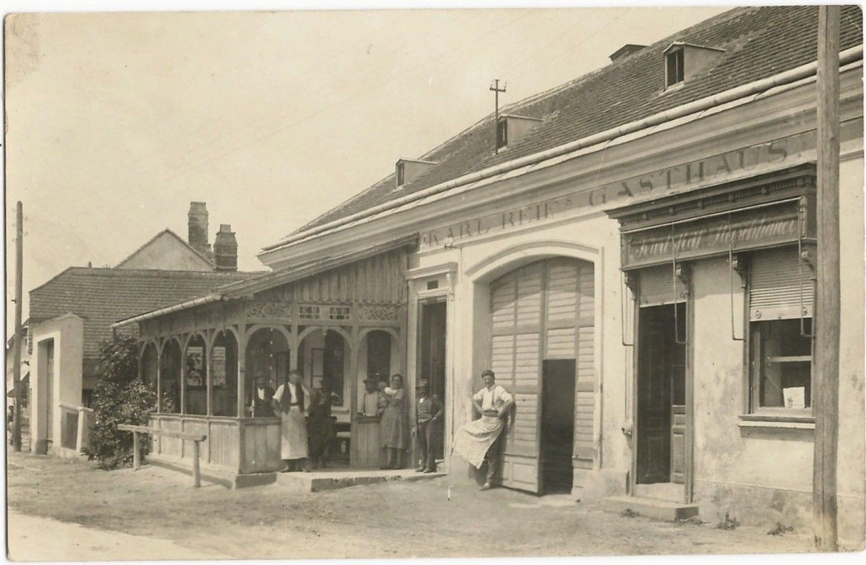 Historická fotografie hostince s lidmi před vchodem.