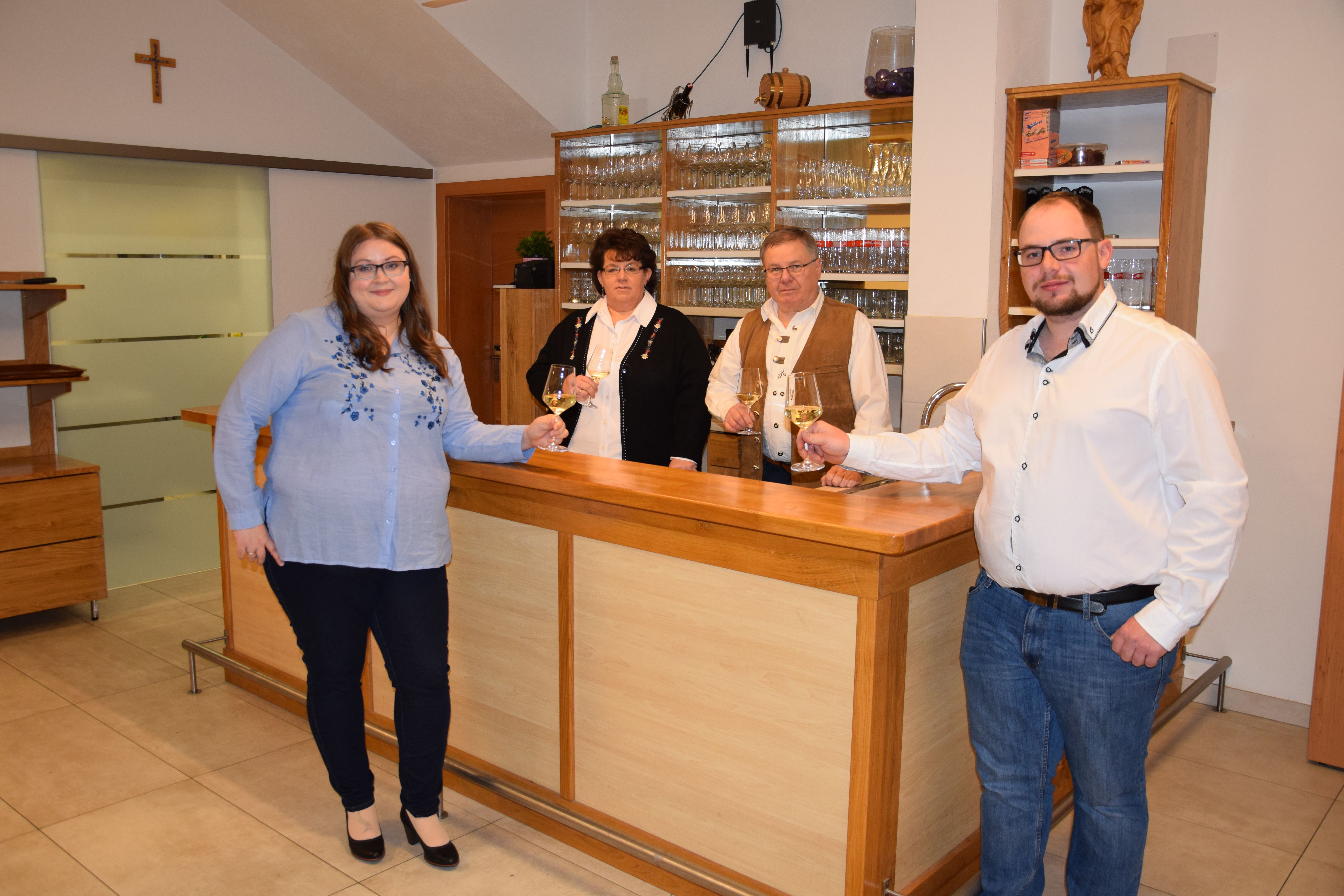 Čtyři lidé stojí u baru a v rukou drží sklenice s vínem.