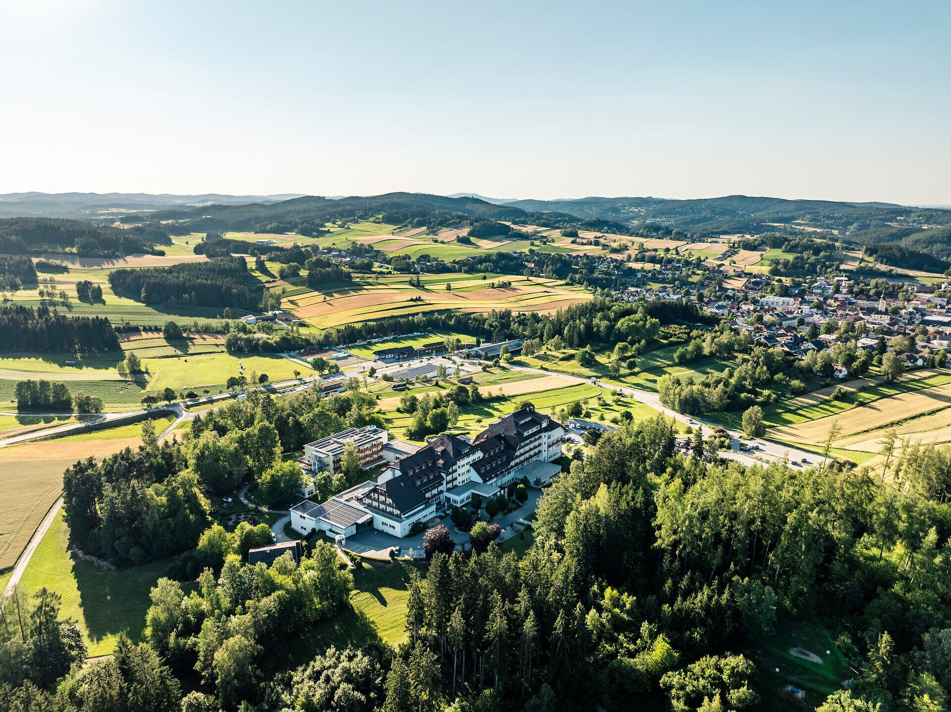 Letecký snímek kardiovaskulárního centra Groß Gerungs ve Waldviertelu, obklopeného loukami, poli, lesem a obcí Groß Gerungs.