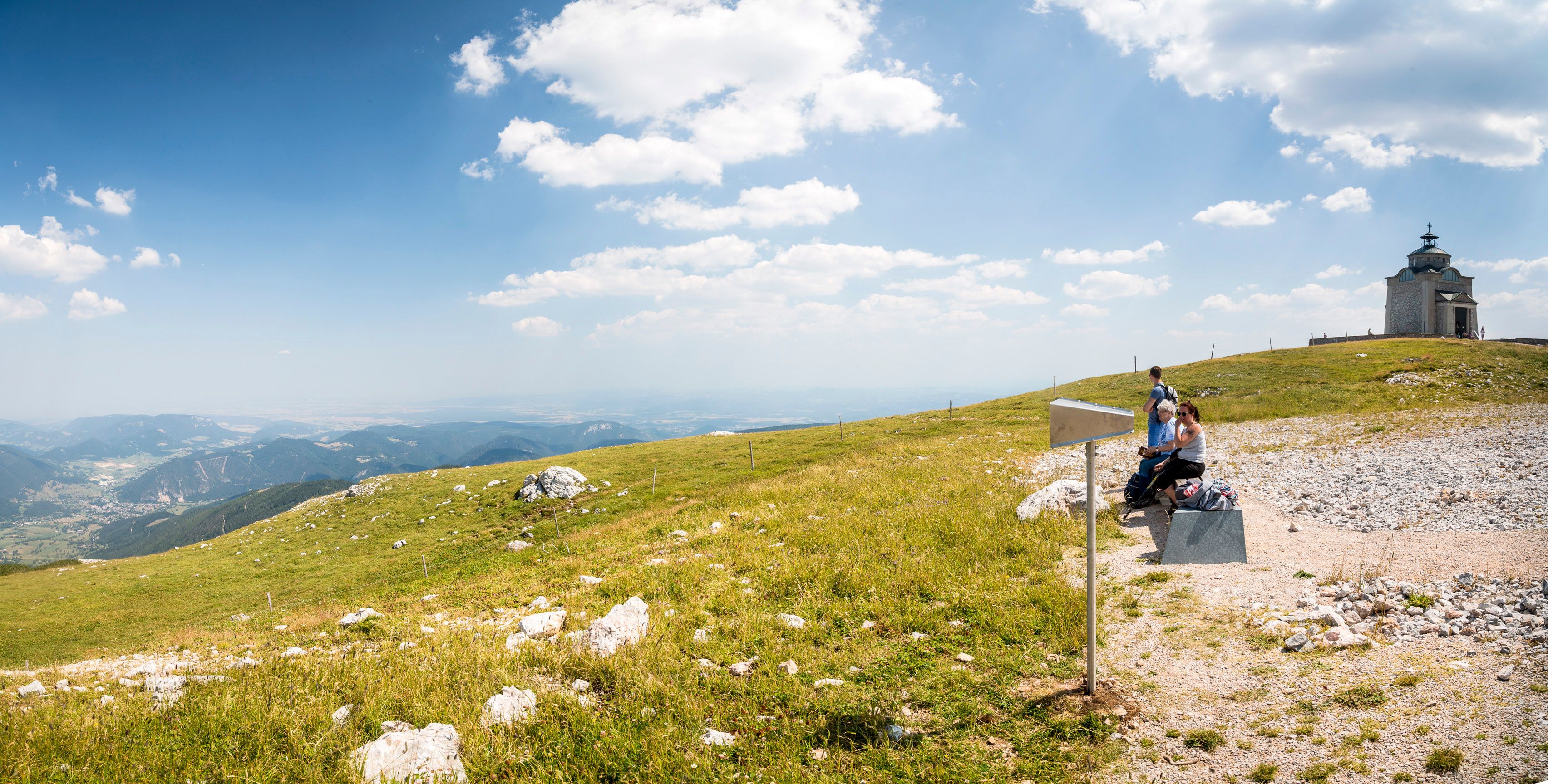 Panoramatický pohled na kostel Elisabeth na Schneebergu s turisty v popředí.