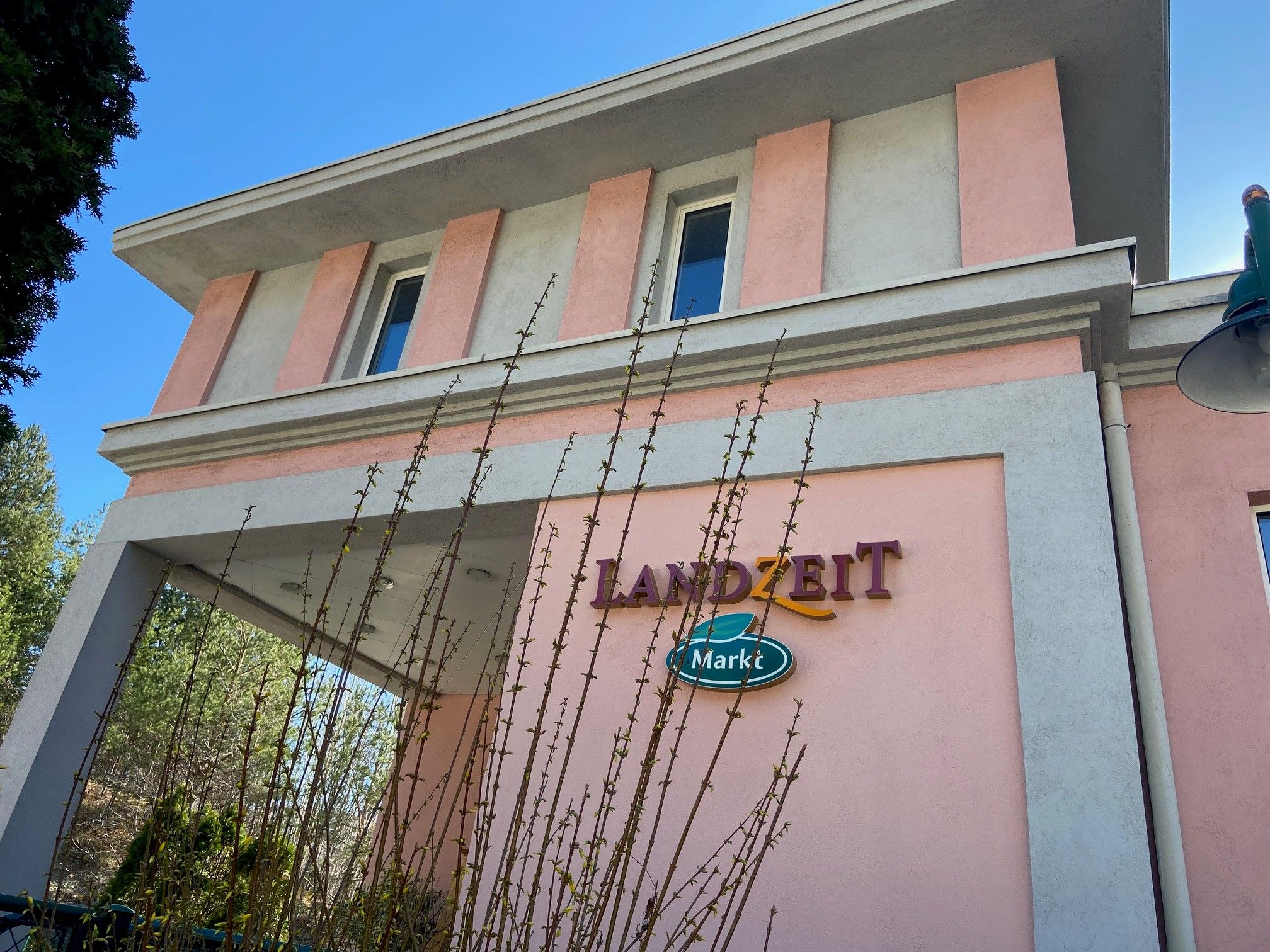 Budova s růžovou a šedou fasádou, nápis "Landzeit Markt".