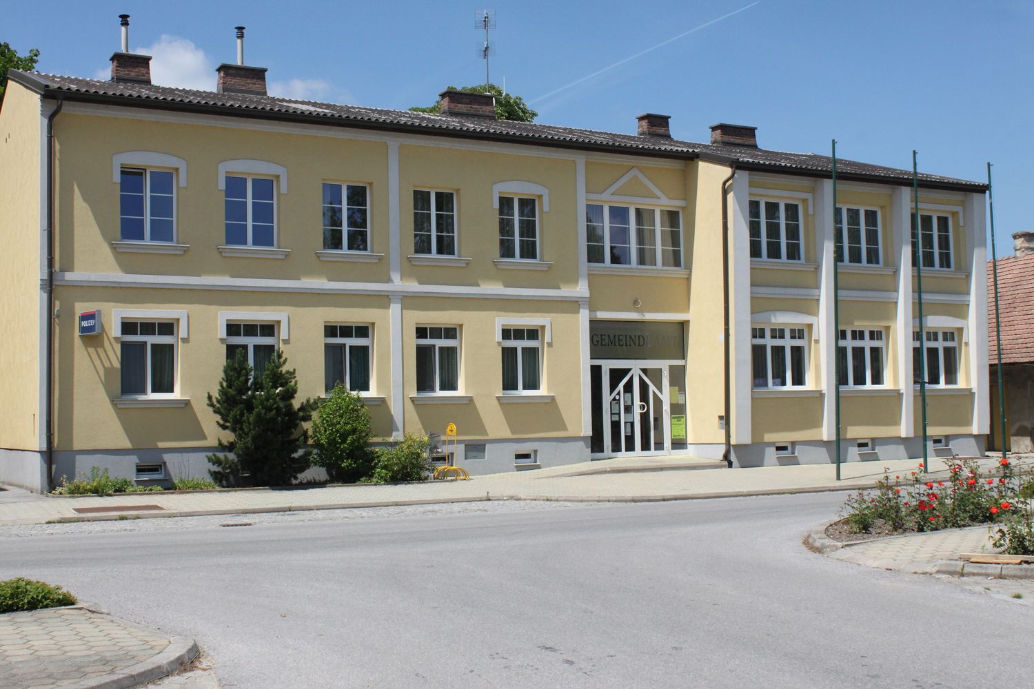 Žlutá budova s nápisem "Gemeindeamt" a několika okny.