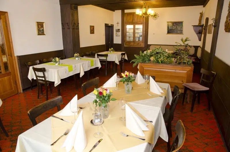 Pohled do interiéru tradiční restaurace s prostřenými stoly a rostlinami.